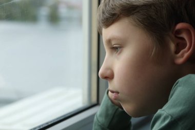 Otizm konsepti. Evdeki pencerenin yanında yalnız küçük çocuk, mesaj için yer var.