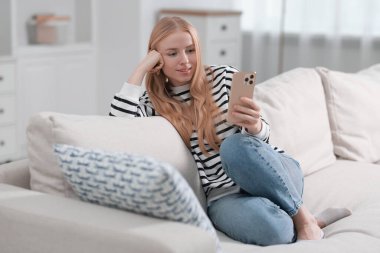 İçerideki koltukta akıllı telefon kullanan gülümseyen kadın.
