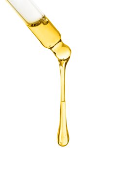 Temel yağ beyaz arka planda pipetten damlıyor