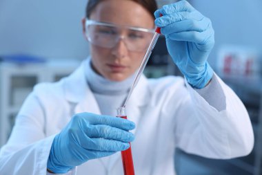Laboratuvar testi. Doktor kan örneğini kapalı alanda test tüpüne damlatıyor, seçici odaklanma