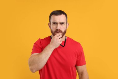 Turuncu arka planda ıslık çalan genç adam.