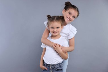 Gri arka planda şirin küçük kız kardeşlerin portresi