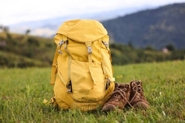 Yeşil çimlerin üzerinde sırt çantası ve yürüyüş ayakkabıları.