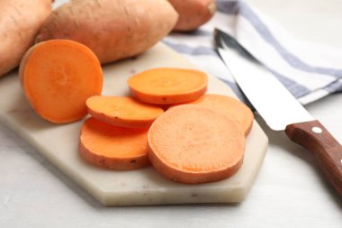 Taze patates, bıçak ve mutfak havlusu beyaz masada, yakın plan.