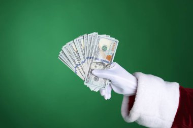 Noel Baba yeşil arka planda dolar banknotları tutuyor, yakın plan. Metin için boşluk