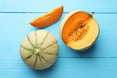Kesilmiş ve olgunlaşmış kavunlar açık mavi ahşap masada, düz yatıyordu.