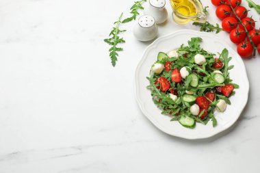 Lezzetli salata roka, mozzarella, domates ve beyaz mermer masada salatalık, düz yatak. Metin için boşluk
