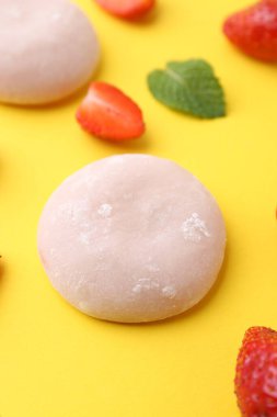 Sarı arka planda lezzetli mochi ve çilekler, yakın plan.