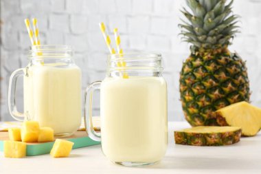 Mason kavanozlarında nefis ananas kokteyli ve beyaz ahşap masada taze meyveler.