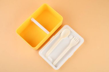 Şeftali arka planında çatal bıçak takımı olan plastik beslenme çantası.