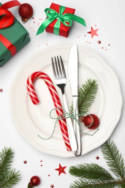 Tabak, çatal bıçak takımı ve beyaz arka planda şenlikli Noel sofrası, düz yatış