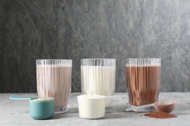 Lezzetli protein kadehleri ve toz tozuyla gri desenli masadaki kepçeler.