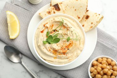 Kırmızı biberli enfes humus, beyaz mermer masada pide ve nohut, üst manzara.