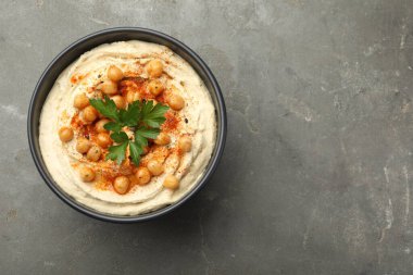 Maydanozlu enfes humus, kırmızı biber ve nohut kasede, gri masada, üst tarafta. Metin için boşluk