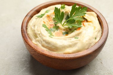 Kırmızı biberli lezzetli humus ve gri arka plandaki kasede maydanoz, yakın plan.