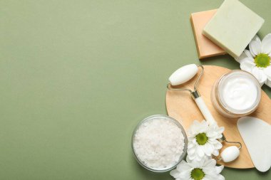 Yeşil arkaplan üzerinde yüz silindiri ve gua sha aracı ile düz konum, metin için boşluk