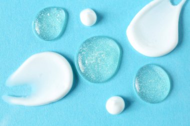 Açık mavi arka planda farklı kozmetik ürünlerinin kokusu, düz yatış