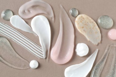 Gri arka planda farklı kozmetik ürünlerinin izleri, düz yatış