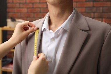 Atölyedeki müşteriye yaka ölçüsü veren profesyonel bir terzi.