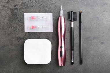 Profesyonel makyaj makinesi, tek kullanımlık kartuşlar ve gri arka planda farklı fırçalar.