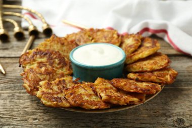 Lezzetli patates krepleri, ekşi krema, menorah ve ahşap masa üzerindeki mumlar, yakın plan. Hanuka bayramı yemekleri.