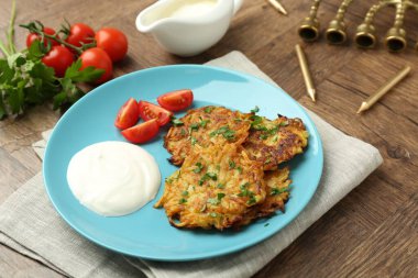 Delicious potato pancakes, menorah and candles on wooden table, closeup. Hanukkah festive food clipart