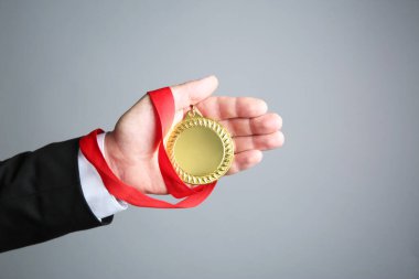 Gri arka planda altın madalyalı adam, yakın plan.