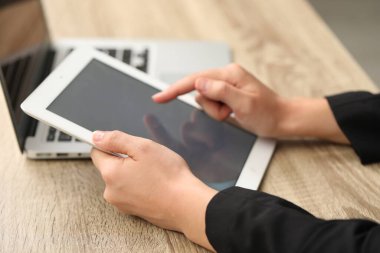 Tabletli ve laptoplu bir iş adamı ahşap masada, yakın plan. Modern teknoloji