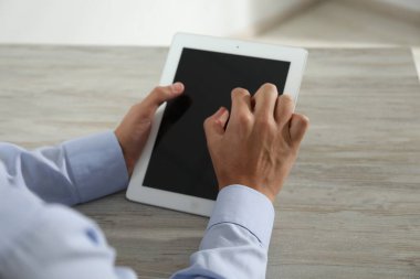 İşadamı ahşap masada tablet kullanıyor, yakın plan. Modern teknoloji