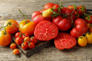 Many different ripe tomatoes on wooden table