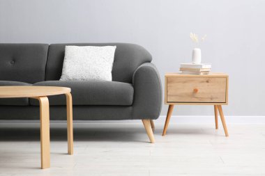 Rahat bir kanepe ve gri duvarın yanındaki masalar.