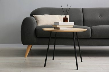 Rahat bir kanepe ve gri duvarın yanındaki masa.