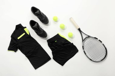 Tenis raketi, toplar ve beyaz arka planda spor giyimi, düz yatış