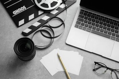 Kamera lensleri, film alkışları ve dizüstü bilgisayarlar gri desenli tabloda, yukarıda.