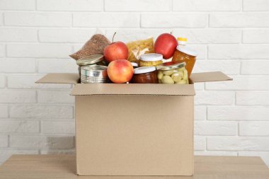 Beyaz tuğla duvarın yanındaki tahta masada bağış yapmak için farklı gıda ürünleri.