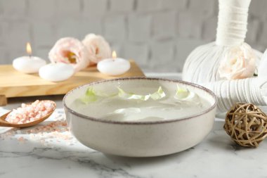 Beyaz mermer masada bir kase su ve yanan mumlarla kaplıca kompozisyonu, yakın plan.