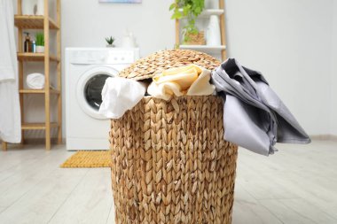 Banyoda yerde çamaşır dolu bir sepet.