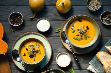 Gri ahşap masada servis edilen lezzetli balkabağı çorbası.