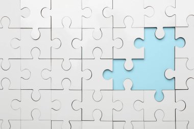 Açık mavi arkaplanda eksik parçaları olan beyaz bulmaca, üst görünüm