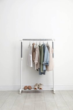 Beyaz duvarın yanında giysi ve ayakkabılarla dizilin.