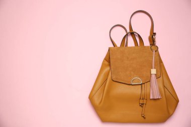 Pembe arka planda deri anahtarlıklı sırt çantası, üst manzara. Metin için boşluk