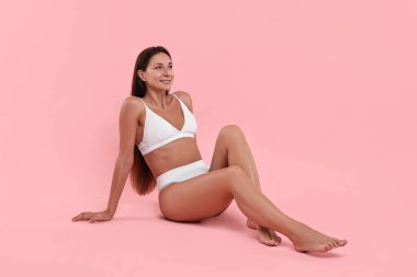 Pembe arka planda poz veren mükemmel ciltli gülümseyen kadın. Vücut bakımı