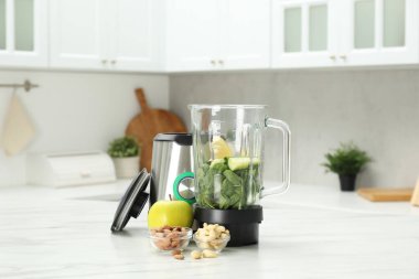 Mutfaktaki beyaz mermer masada smoothie için malzemeler içeren modern blender.