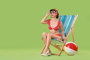 Bikini giymiş kadın yeşil arka planda katlanır sandalye, metin için yer