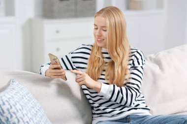 İçerideki koltukta akıllı telefon kullanan gülümseyen kadın.