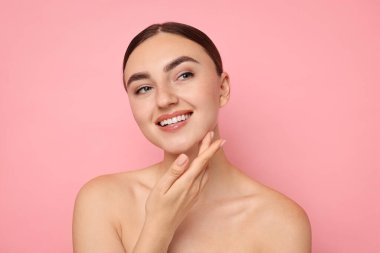 Yüz masajı. Pembe arka planda sağlıklı ciltli güzel bir kadın.