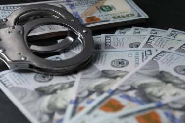 Yozlaşma. Kelepçe ve dolar banknotları siyah masaya, yakın plan.