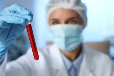 Laboratuvar testi. Kapalı alanda kan örneği olan test tüpü tutan doktor, seçici odaklanma