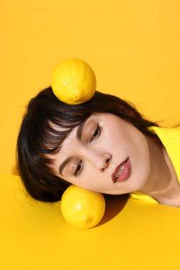 Young woman with lemons on yellow background clipart