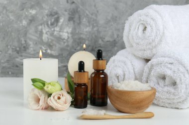 Beyaz masa üzerinde kozmetik ürünleri ve havlularla spa kompozisyonu